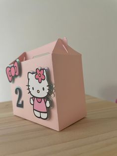 a pink hello kitty gift box sitting on top of a wooden table