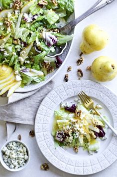 a white plate topped with salad next to two lemons and a bowl of dressing