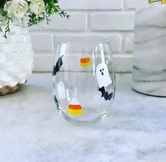 two wine glasses decorated with halloween decorations on a marble countertop next to a vase