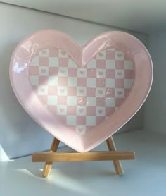 a pink and white heart shaped plate on a wooden stand