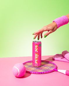 a woman's hand reaching for a can of yogurt on a tennis racket