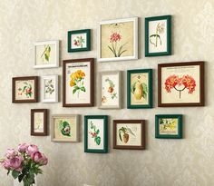 there are many framed pictures on the wall with flowers in vases next to them