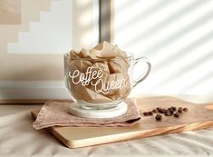 a glass cup filled with coffee sitting on top of a wooden cutting board