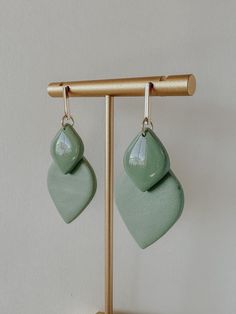 the earrings are green and have small tears hanging from them on a wooden stand