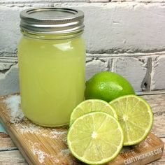 limes and sugar sit on a cutting board next to a jar of lemonade