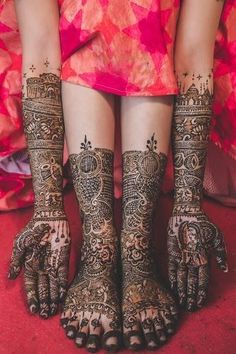 the feet and hands of a woman with henna tattoos on their legs, both covered in