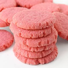 a pile of pink cookies sitting on top of a white table next to each other