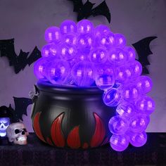 a pot filled with lots of purple lights on top of a table next to a skull