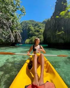 a woman sitting in a yellow kayak on the clear blue water near some cliffs