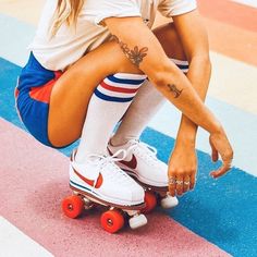 a woman sitting on top of a skateboard wearing white socks and knee high socks