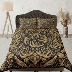 a bed with a black and gold comforter on top of it next to a lamp