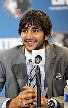 a man wearing a suit and tie sitting at a table in front of a microphone