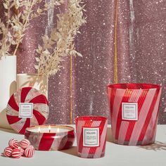 three red candles sitting on top of a table next to candy canes and flowers