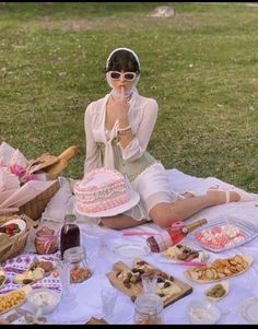 a woman sitting on top of a blanket next to a cake