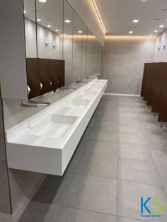 a row of sinks in a public restroom with mirrors on the wall and lights above them