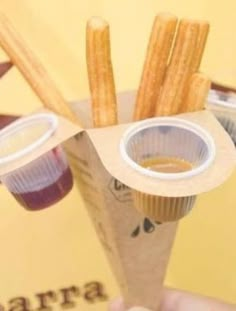 a person holding up a paper cup with some food in it and french fries sticking out of it