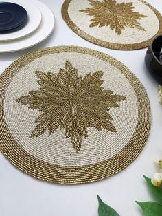 two placemats on a table with plates and flowers in the center, one is gold