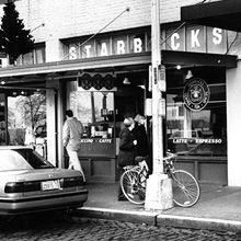 a black and white photo of people walking in front of a store