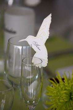 a table topped with wine glasses and a paper bird