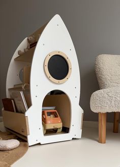 a toy rocket ship with books and toys in it on the floor next to a chair