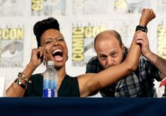 a man and woman sitting next to each other in front of a table with water bottles