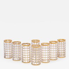 six gold and clear glass candlesticks in the shape of squares, set against a white background