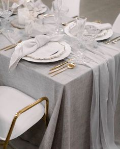 the table is set with white and gold place settings, silverware, and napkins