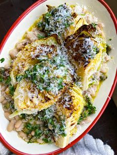 a white plate topped with artichoke and beans covered in parmesan cheese