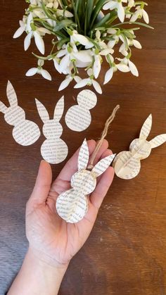 someone is holding some paper cut outs in front of a bouquet of flowers and greenery