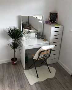 a white desk with a mirror, chair and potted plant