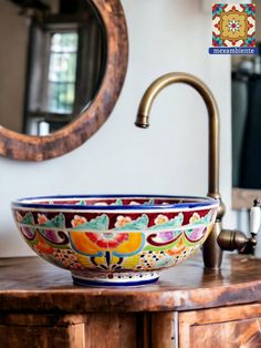 a bowl shaped sink sitting on top of a wooden counter next to a mirror and faucet