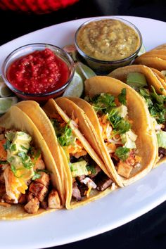 several tacos on a plate with salsa and guacamole