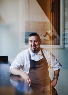 a man wearing an apron and smiling at the camera