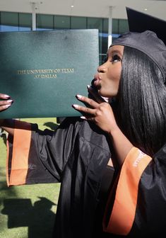 a woman in graduation gown holding up a book