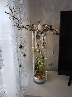 a vase filled with ornaments and lights on top of a white shelf next to a window