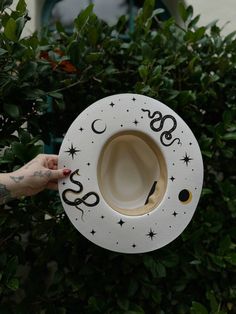 a person is holding up a white cat house with black letters and stars on it