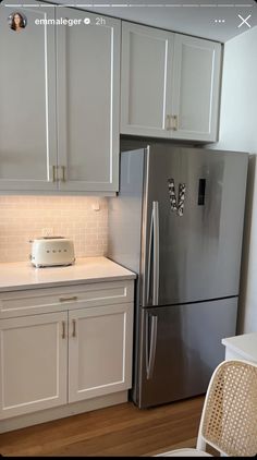 a silver refrigerator freezer sitting inside of a kitchen next to white cabinets and drawers