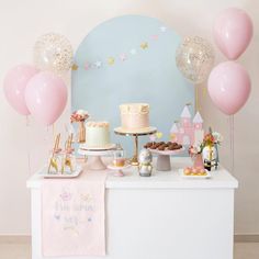 a table topped with lots of cake and balloons