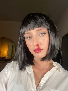 a woman with black hair and red lipstick on her face, wearing a white shirt