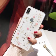 a woman's hand holding an iphone case with flowers on it