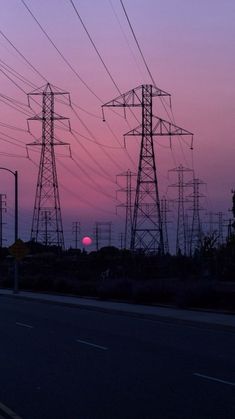 the sun is setting behind power lines in an area that looks like it's going down