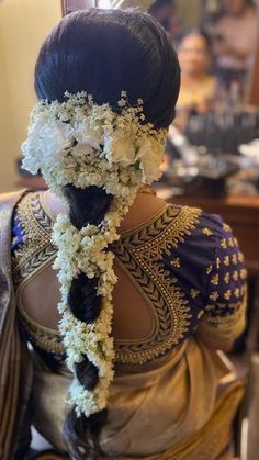 the back of a woman's head with flowers in her hair and an elaborate braid