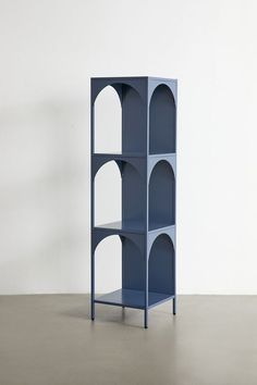 a tall blue shelf sitting on top of a cement floor next to a white wall