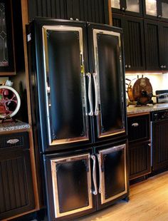 a kitchen with black cabinets and stainless steel refrigerators in it's center island