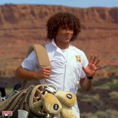 a man is holding two stuffed animals in his hands while standing next to a mountain