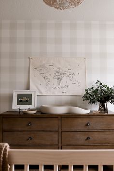 a baby crib in front of a wall with a map on it and a potted plant