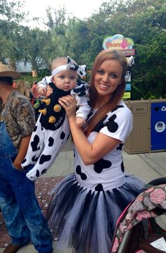 a woman is holding a baby dressed as a cowgirl and wearing a costume that has been made to look like a cow