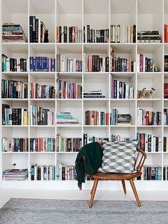 a chair sitting in front of a book shelf filled with books