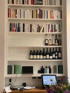 a laptop computer sitting on top of a wooden desk in front of a book shelf filled with books