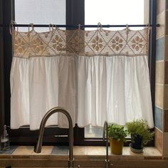 a kitchen sink under a window next to a potted plant